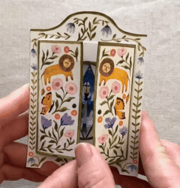 a gif of a tunnel book being opened to show its three-dimensional scene inside of the winter scene and lamp post through the wardrobe in Narnia