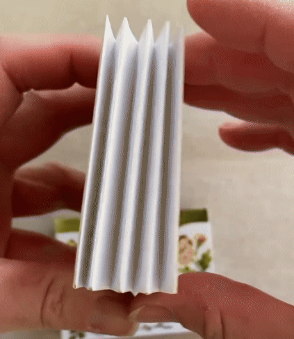a gif of a tunnel book being turned to show its folded sides and the three-dimensional scene of a garden inside