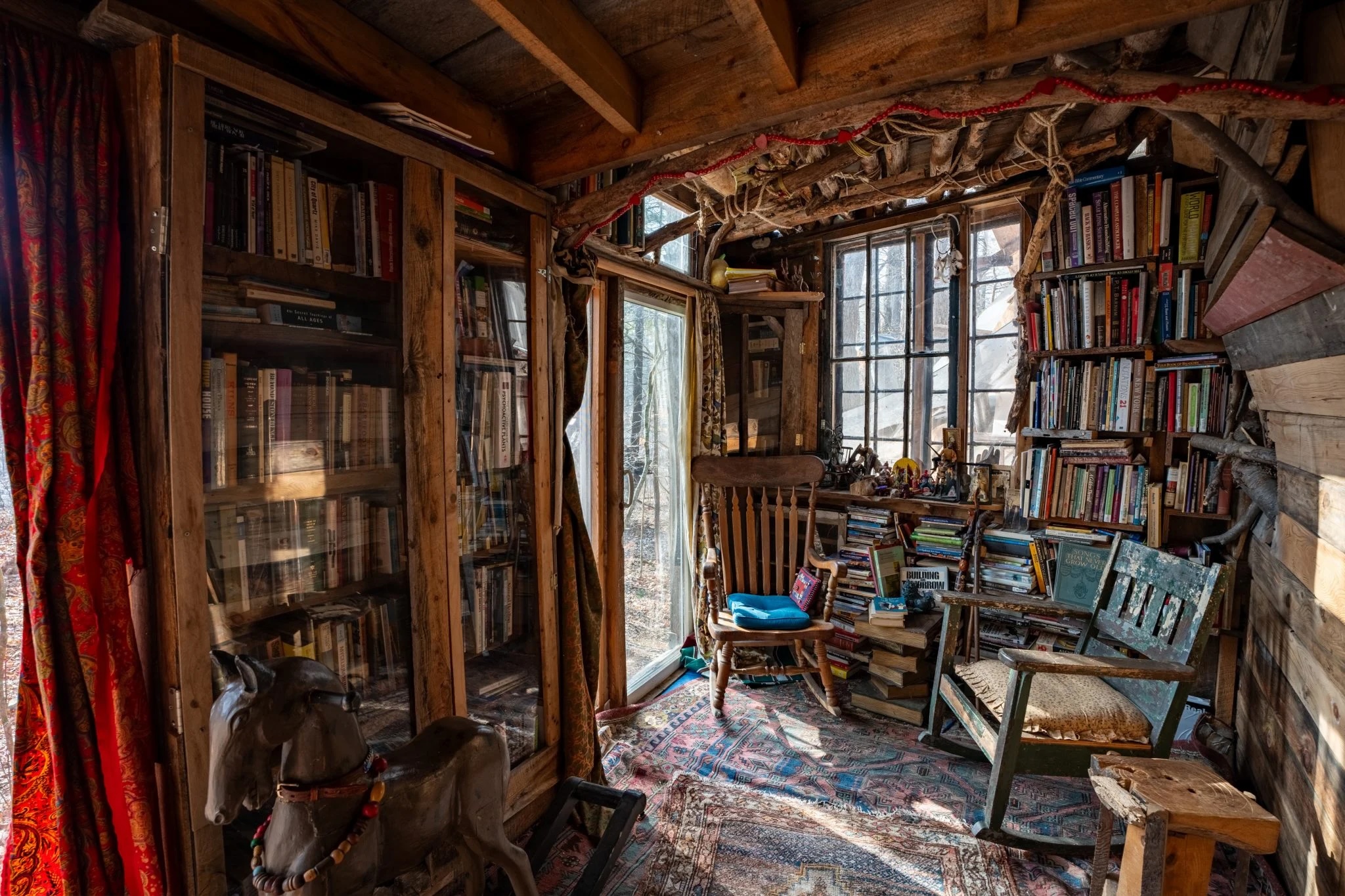 the interior of handbuilt cabin with a chair, bookshelves, and lamps