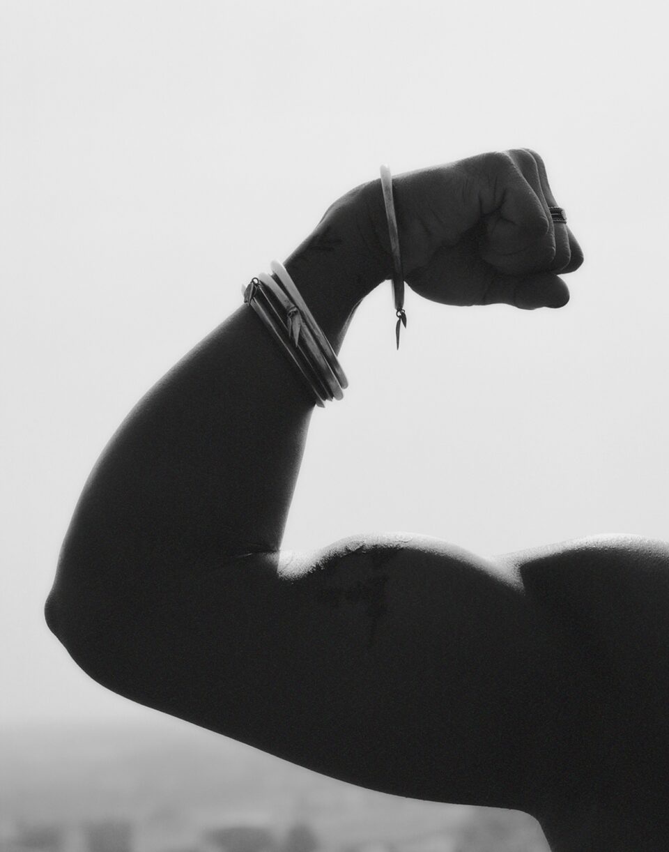 a black and white image of an arm with bangles flexing